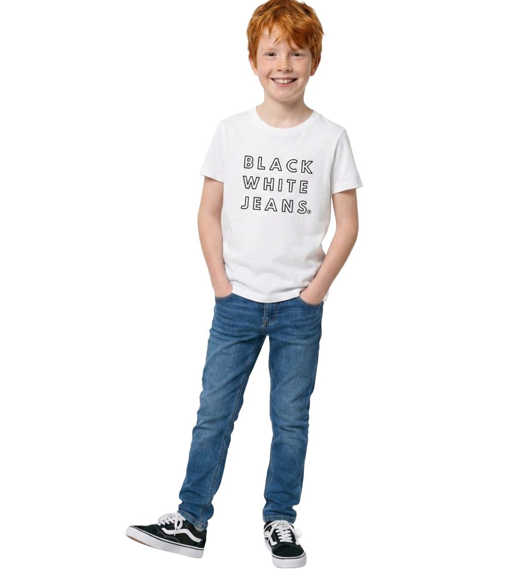 A smiling boy posing in the Black White Jeans Everyday kids organic white t-shirt, featuring the signature black text logo centered on the chest, styled with jeans.