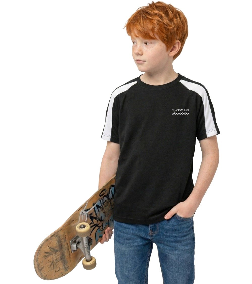 Lifestyle shot of a skater holding a skateboard, wearing the Black White Jeans Kids Performance Black Tee with contrast raglan sleeves and printed checker logo.