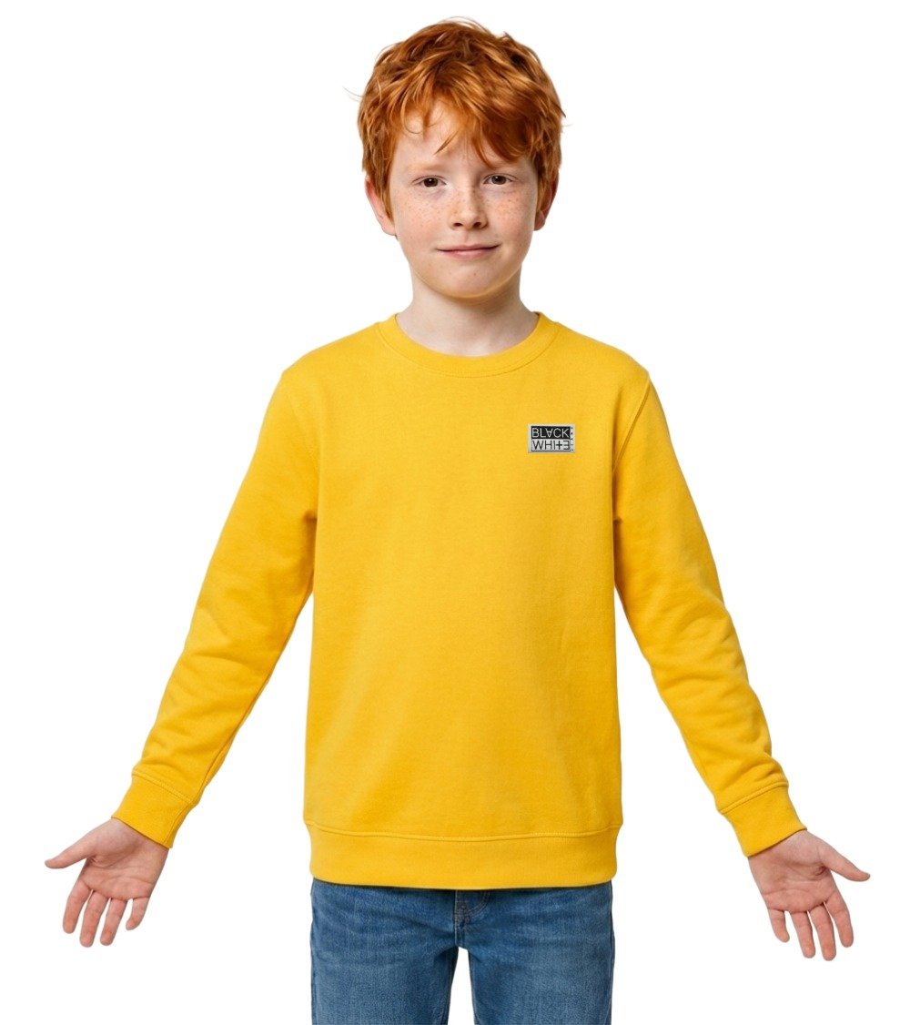 Ginger boy Leo posing in a yellow organic sweatshirt for kids with woven brand patch