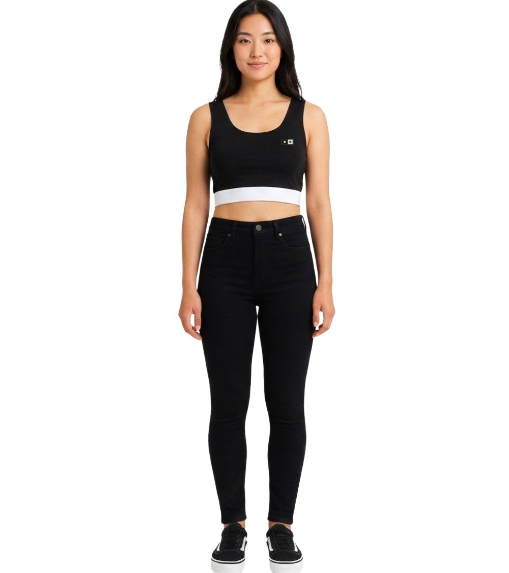 Model wearing black urban style crop top with white hem paired with black skinny jeans for streetwear look.